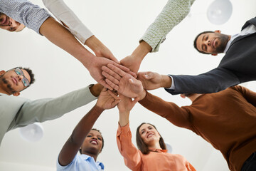 Diverse business team joining hands. Mixed race group of young people standing in circle and...