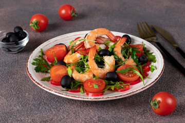 Salad with shrimps, arugula, cherry tomatoes and black olives with olive oil on brown background
