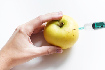 yellow apple and syringe with nitrates isolated on a white background. Pesticides and nitrates are injected by a scientific worker into an apple with a syringe. GMO food ingredient concept