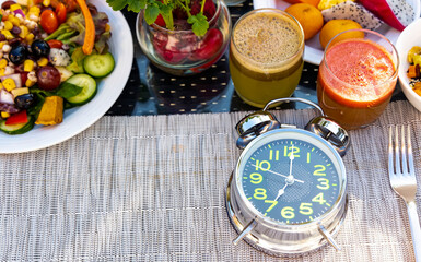 Selective focus of the clock  with a Breakfast in the morning as  Diet plan with alarm clock as Interval fasting diet concept
