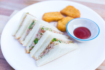 Tuna with vegetable sandwich were served with chicken nuggets and tomato sauce as a breakfast meal in the morning.