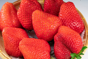 Red Strawberries in Bamboo basket, Fresh Amaoh Strawberry in a wooden bowl on white background.