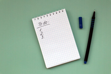 Notebook with to do list on green background and pen with copy space.
