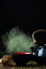 Match green tea ceremony. Teapot, whisk and splash on dark background