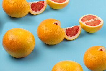 a whole grapefruit and sliced ​​grapefruits are arranged in a row on a blue background. Orange grapefruits in a group with shadows on a blue background