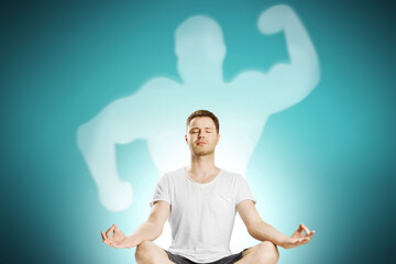 Abstract image of attractive european guy meditating with strong muscle shadow on blue wall...