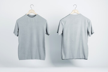 Two blank grey t-shirts hanging in the air with copyspace for your logo on abstract light...