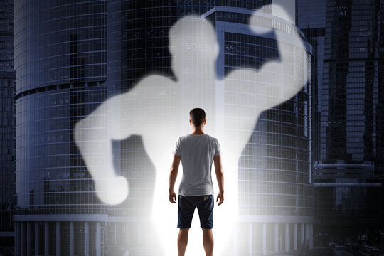 Abstract image of casual young guy with strong muscle shadow on blurry city background. Confidence and strength concept.