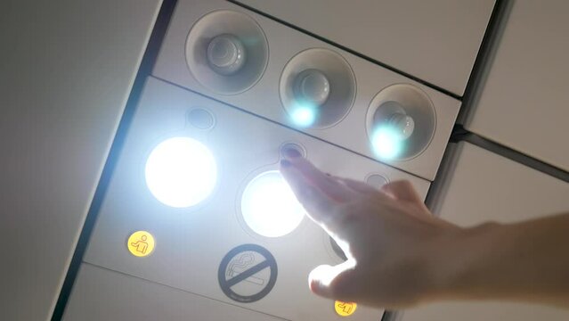 Woman's hand switch on personal light above seat on airplane. Comfort flight. button on console panel onboard for passenger