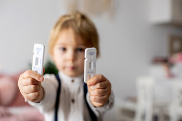 Child, holding  two home made covid 19 SWAB antigen test, home allowed tests, showing positive and...