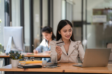 Young woman holding credit card and using laptop computer. Online shopping concept.