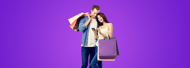 Love, holiday sales, shop, retail, consumer concept - happy couple with shopping bags, looking at mobile phone. Valentines Day holiday. Purple violet color background. - obrazy, fototapety, plakaty