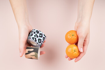 Female hands hold kinesio tapes for body care and tangerines. Weight loss and cellulite control concept 