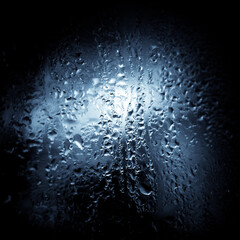 Close up image of wet glass in blue monochrome. Wet surface background.