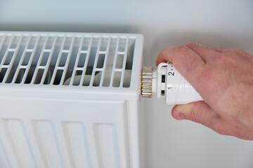 Hand adjusting temperature on heating radiator thermostat, Turning heat radiator knob to control heat in home