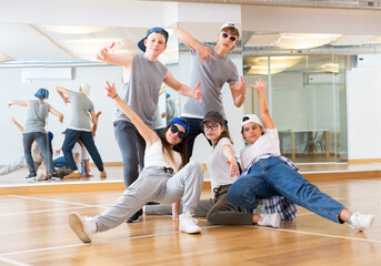 Positive teen girls and boys posing in dance studio during hip hop class