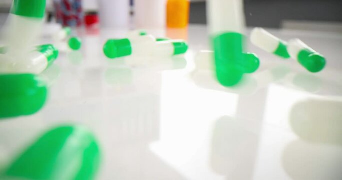 Lot of white green medical capsules falling on table closeup 4k movie slow motion