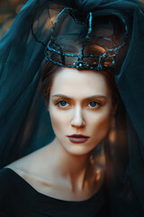 Fantasy Photo portrait of a black queen with a black crown and black tulle with passing sunbeams. 