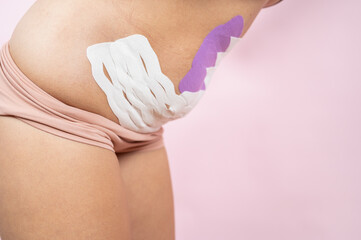 Kinesio medical tapes of the flabby belly of a young woman on pink background. Recovery after childbirth
