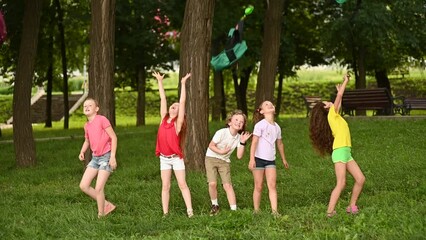 group of school children rejoice at the beginning of the summer holidays, throw up their school backpacks and laugh.
