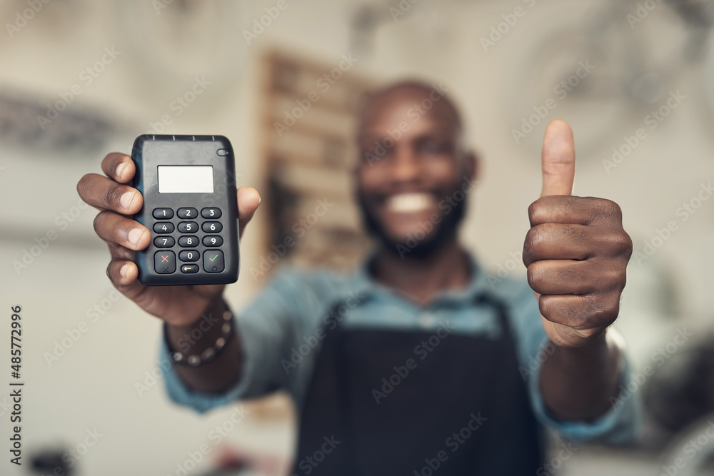 Poster were covid safe. shot of an unrecognizable man standing in his shop and holding a card machine while