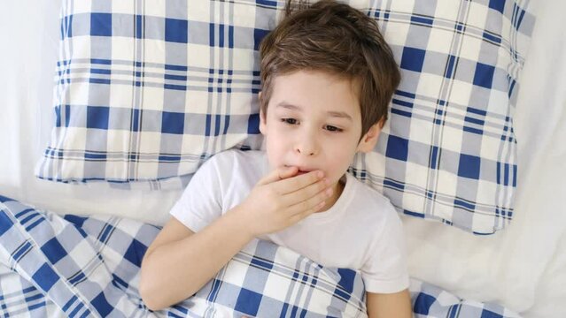 sick coughing boy kid lying in bed at home. ill child with severe cough lying in bed at home. Childhood, healthcare and medicine concept
