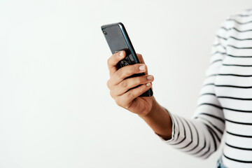 Friends are never far away with your smartphone. Cropped shot of a woman using a smartphone against a white studio background.