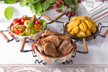 Homemade fried potato slices, assorted pickles, rabbit stewed in the oven. National Moldavian, Romanian, or Ukrainian cuisine. Traditional dishes in an authentic interior.