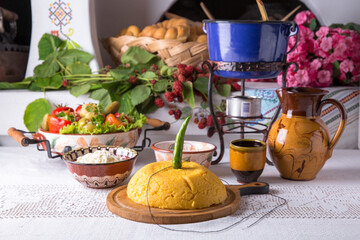 Corn porridge, polenta, hominy with pickles, cottage cheese, sour cream. National Moldavian, Romanian, or Ukrainian cuisine. Traditional dishes in an authentic interior.