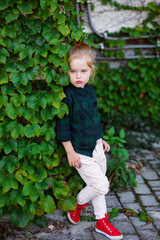 Street fashion kid, pretty little girl in jeans with shopping bag near colorful wall outdoors
