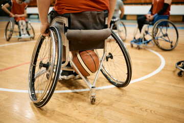 Rear view of basketball player in wheelchair with his teammates on sports court.