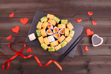 Heart shaped of sushi rolls for Valentines Day on a dark wooden background. Flat lay.