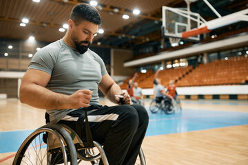 Obraz premium Basketball player with disability strapping his legs on wheelchair before sports training.