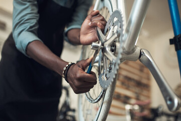 We dont want this falling off. Shot of an unrecognizable man standing alone in his shop and repairing a bicycle wheel.