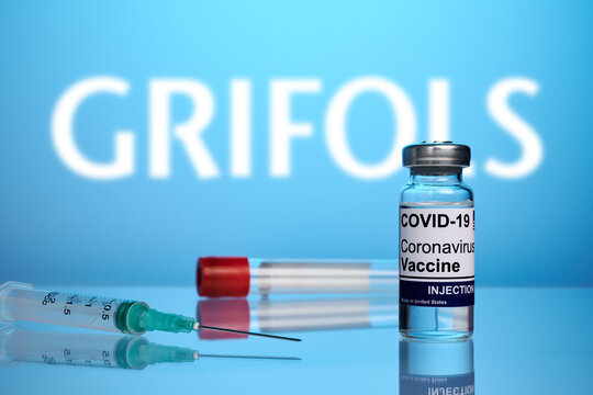 Krasnoyarsk, Russia - April 29, 2021: Grifols Covid vaccine and syringe - photo on a blue gradient background. Antivirus vaccine against coronavirus infection. Blurred Grifols logo for drugstores.