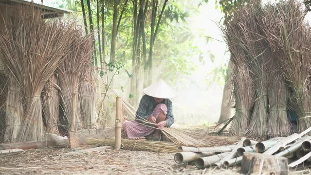 Asia life old femen  grandmother working in outdoor.
Old lady elderly serious living in the countryside of life rural people in thailand . Weaving material grass roof groof bamboo mak
