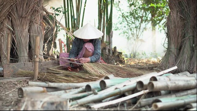 Asia life old femen  grandmother working in outdoor.
Old lady elderly serious living in the countryside of life rural people in thailand . Weaving material grass roof groof bamboo mak