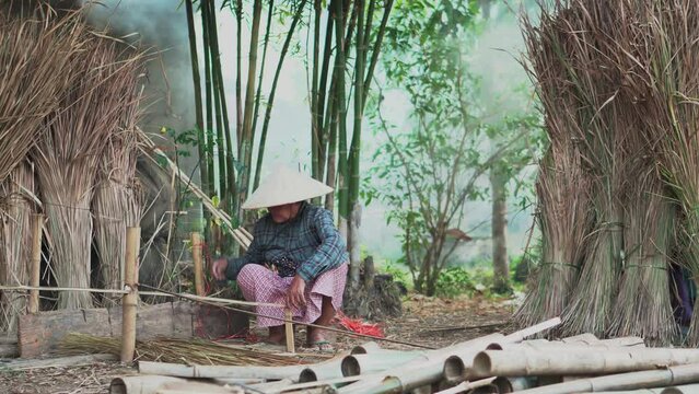 Asia life old femen  grandmother working in outdoor.
Old lady elderly serious living in the countryside of life rural people in thailand . Weaving material grass roof groof bamboo making.