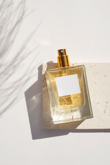 Transparent bottle of perfume with white label on stone plate on a white background. Fragrance...