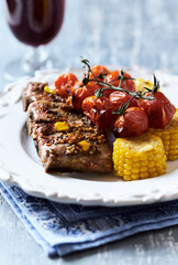 Fried pork ribs with cherry tomatoes and sweet corn. Close up.