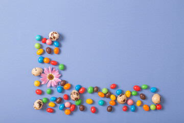 easter chocolate eggs and flowers on blue paper background