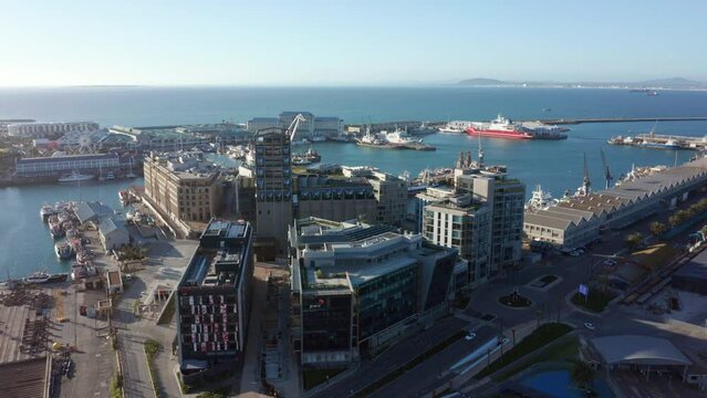 Aerial shot orbiting around some buildings in Cape Town's harbor district with the V&A Waterfront an ocean in the background