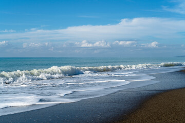 Sand beach with waves blue sea and blue sky and white clouds