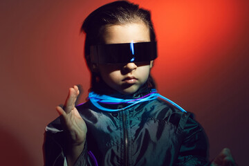 blur portrait cyberpunk boy child in vr glasses in blue and red tones with wires on a red background
