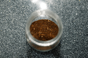 Ground coffee, a ground coffee bean for brewing in a moka pot, a black granite countertop and coffee in a jar. Selective focus, noise effect.