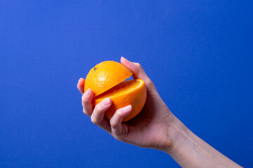 woman's hand holding a cut ripe orange