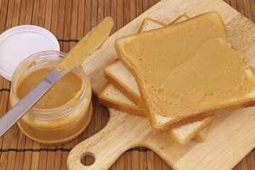 Peanut butter spread and table knife with bread slices on cutting board