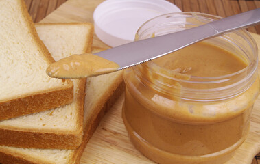 Close up of peanut butter spread and table knife with bread slices 