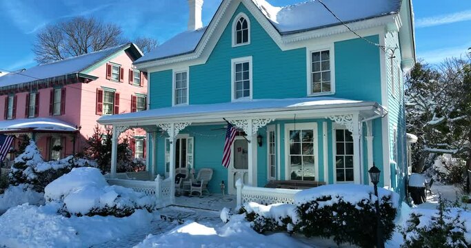 Victorian homes in USA in fresh winter snowfall. Rising aerial pedestal establishing shot. American flag on front porch entrance.