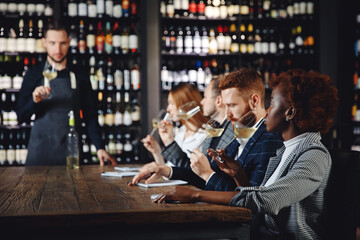 Control group people checks quality of new alcoholic product of white wine, tests taste and aroma with sommelier man